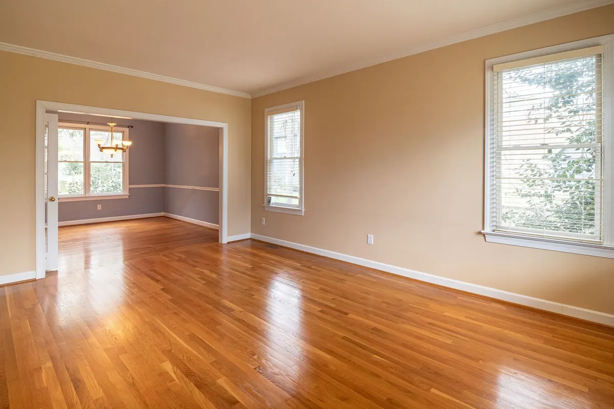 Bright empty living room with polished hardwood floors and large windows