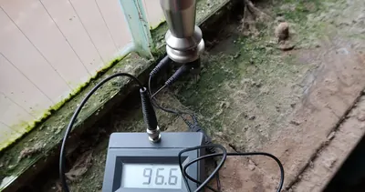 Moisture meter probes on a moldy window sill with a high reading